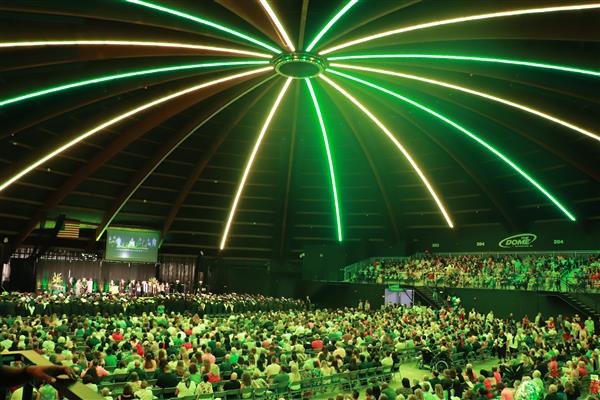 The dome lights in alternating green and gold colors reflecting on the crowd below.